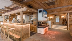 A rustic interior with a wooden bar area, seating, and a staircase leading to an upper level. - Hotel Pinzger (Tux)