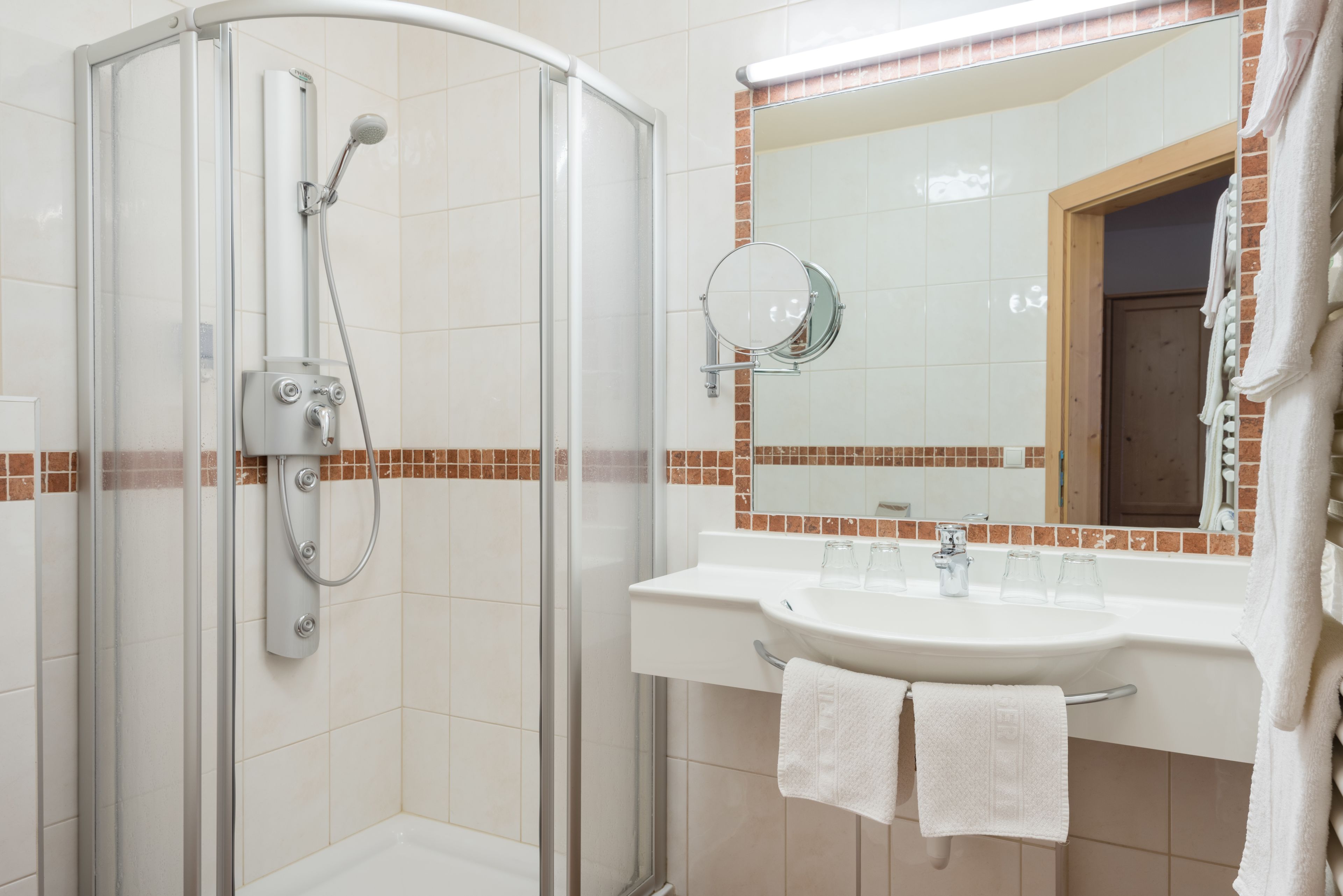 A modern bathroom with a glass-enclosed shower, a sink with a mirror, and a towel rack.