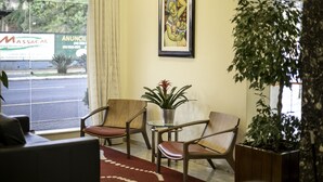 Un espace d’accueil doté d’une grande fenêtre, d’une œuvre d’art encadrée et de plusieurs chaises.