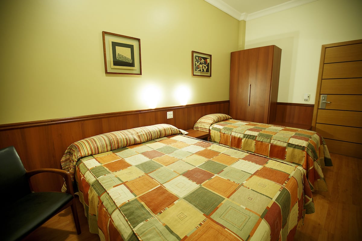 A room with two beds, wooden walls, and a wardrobe.