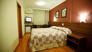 Une chambre d’hôtel avec un lit, un bureau, une chaise et un téléviseur.