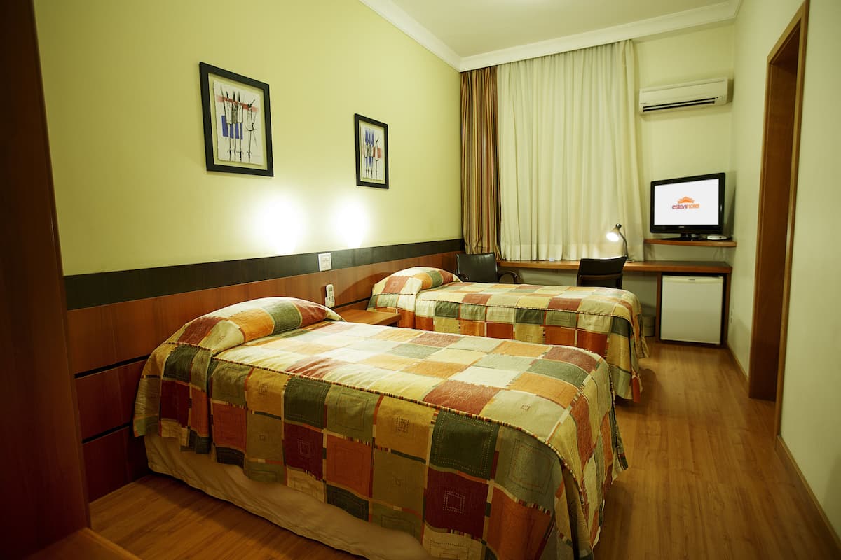 A hotel room with two beds, a desk with a computer, and a television.