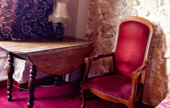 Una mesa de madera con tapa curvada y una silla tapizada de color rojo con respaldo alto.