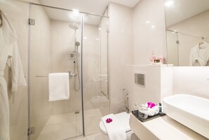 Un baño moderno con ducha envuelta en vidrio, un lavabo blanco y un espejo grande.
