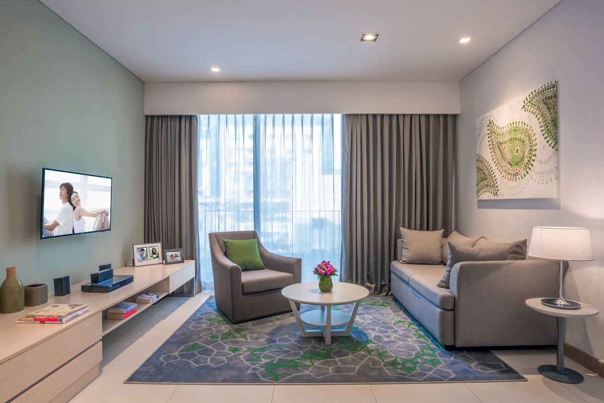 Ein modernes Wohnzimmer mit einer Couch, einem Sessel, einem Couchtisch und einem Fernseher an der Wand.