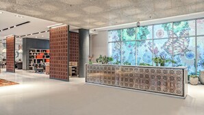 Un vestíbulo moderno con un techo decorativo, una recepción y un amplio ventanal con vistas a un jardín floral.