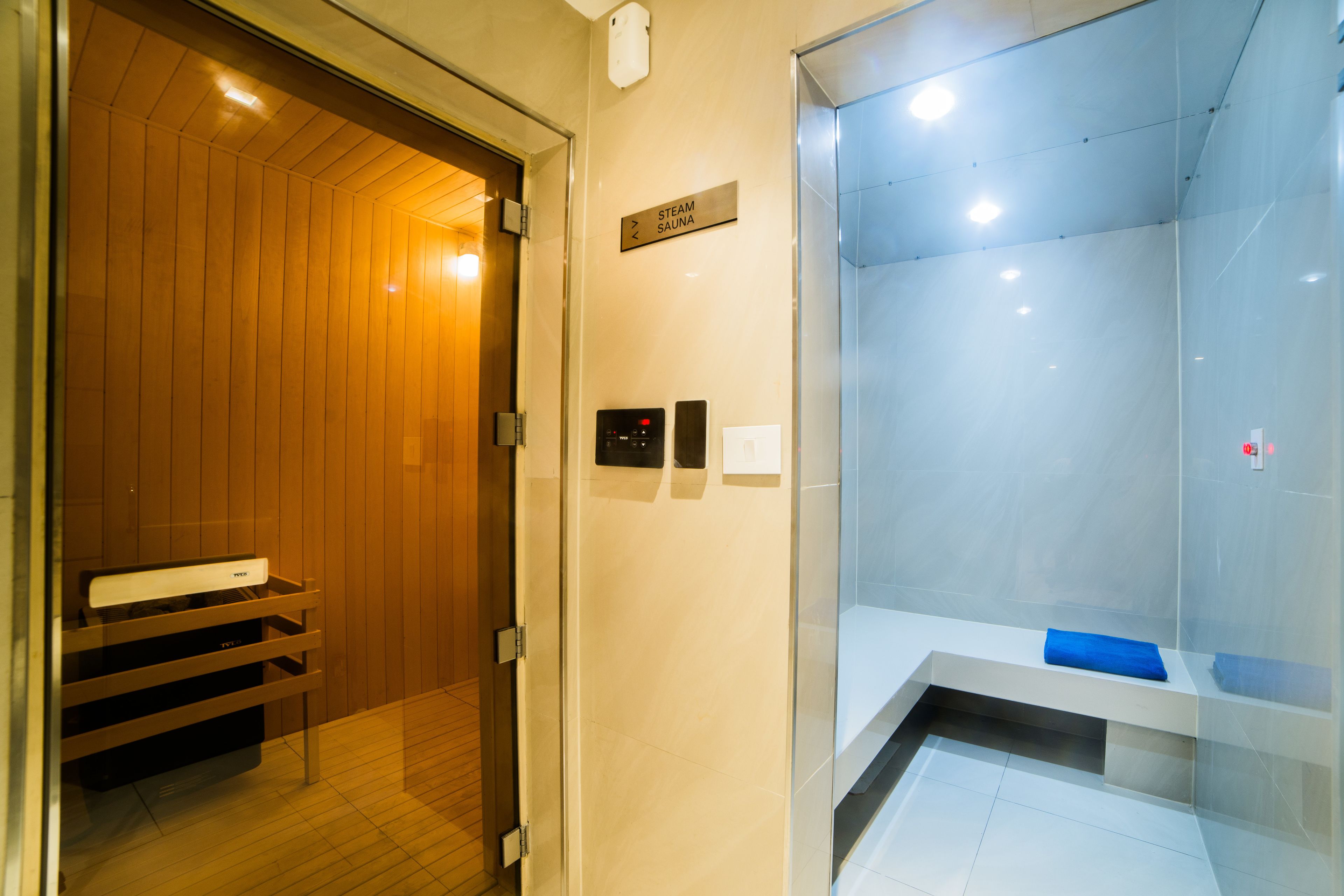 A modern bathroom with a wooden vanity, a glass shower enclosure, and a sign indicating a steam sauna.