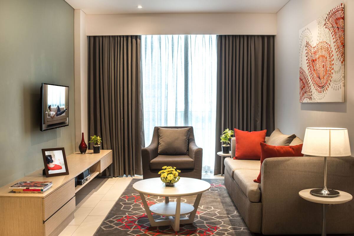 Ein modernes Hotelzimmer mit einer Couch, einem Sessel und einem kleinen Tisch mit Blumen in einer Vase.