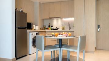 Una cocina moderna con lavadora integrada, una mesa de comedor con cuatro sillas y una variedad de electrodomésticos y utensilios de cocina.