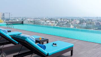 A rooftop pool area with lounge chairs and a city view.