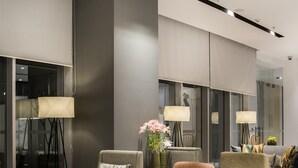 Un salón moderno con asientos cómodos, incluyendo un sofá y sillones, una mesa de centro y dos lámparas de pie.