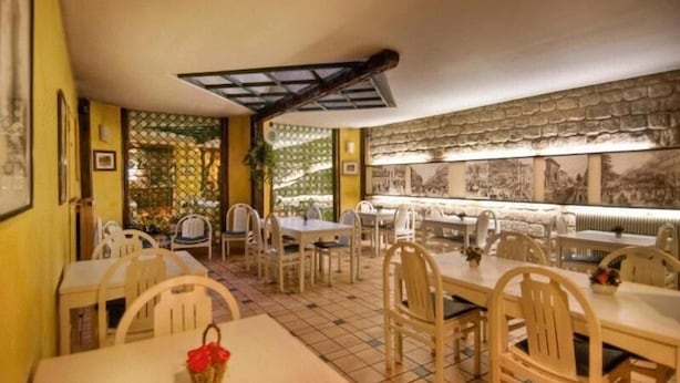 A restaurant with multiple tables and chairs, a tiled floor, and a patterned wall. - Hôtel Le Faubourg (Paris)