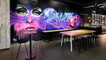 Una zona de bar con un letrero de neón, una mesa larga y varios taburetes.