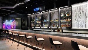 Un espace bar agrémenté d'un néon, de tabourets et d'étagères remplies de bouteilles.