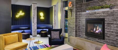 A modern lounge area with a fireplace, seating, and a neon sign.