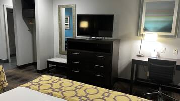 Une chambre d’hôtel comprenant un lit, un bureau avec une chaise, une télévision, une commode et une lampe.