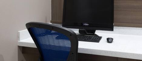 A computer desk with a monitor, keyboard, and mouse.