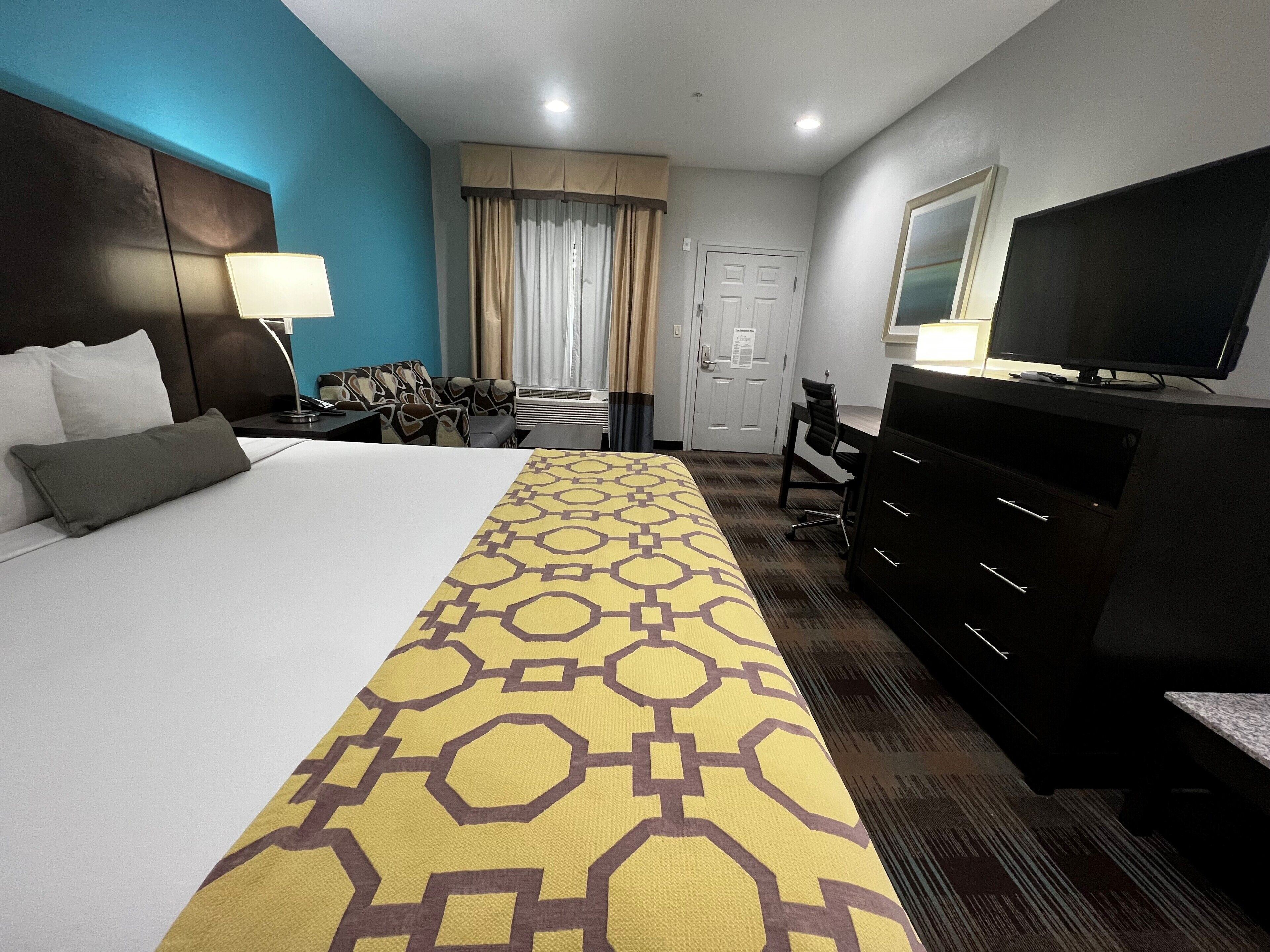 Una habitación de hotel con una cama grande, un escritorio, un televisor y un aparador.