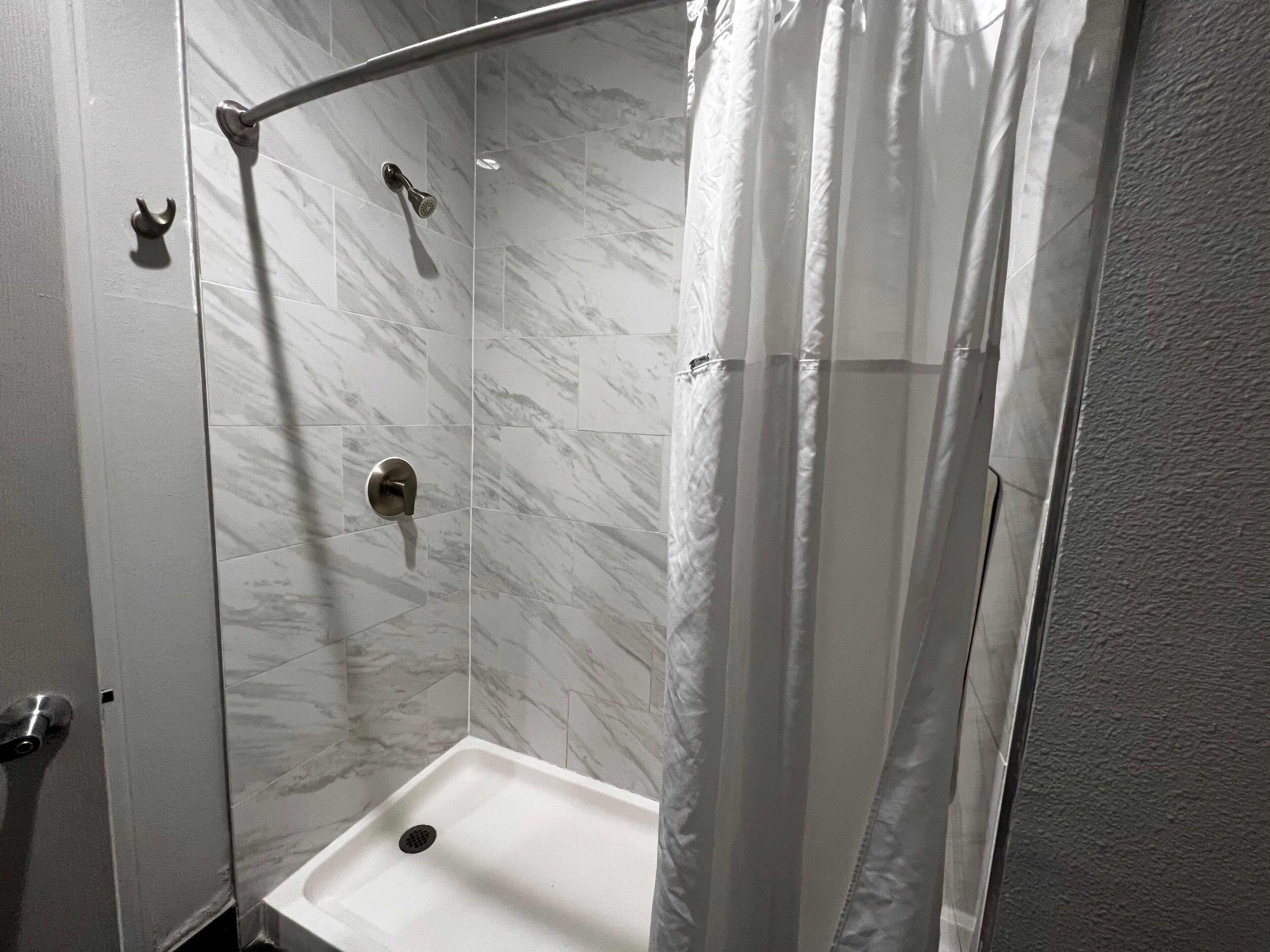 A shower with a curved door and a drain.