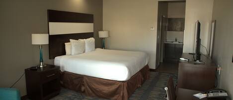 Una habitación de hotel con una cama grande, mesitas de noche, un escritorio y una silla.