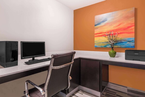 A modern office space with a desk, two monitors, a keyboard, a chair, a vase with flowers, and a printer.