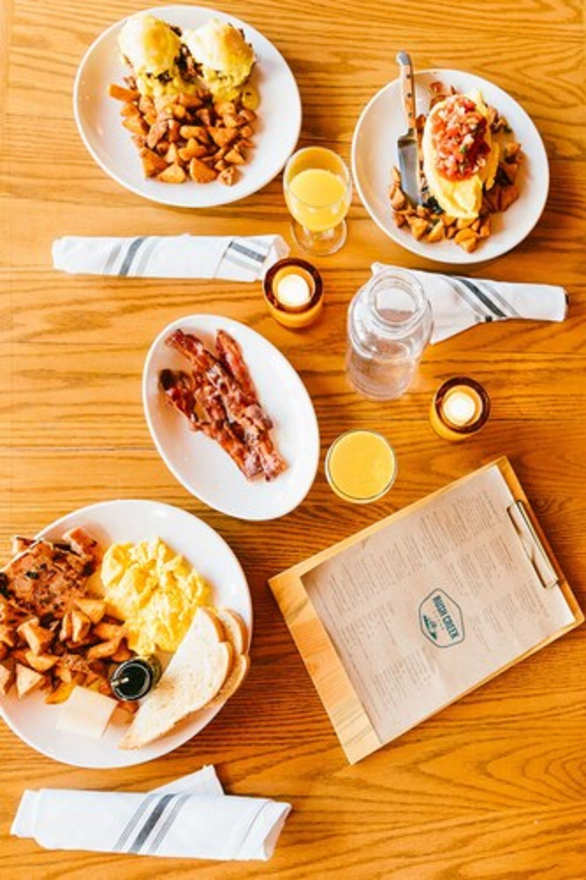 A breakfast setting with plates of food, a menu, and a candle.