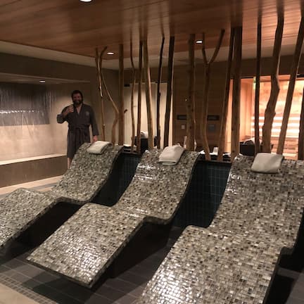 A spa area with multiple massage chairs, wooden decor, and a person taking a selfie.