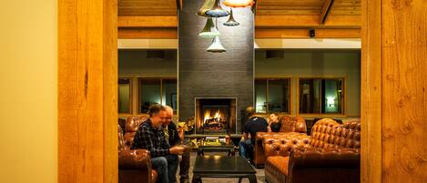 A cozy lounge area with leather sofas, a fireplace, and hanging pendant lights.