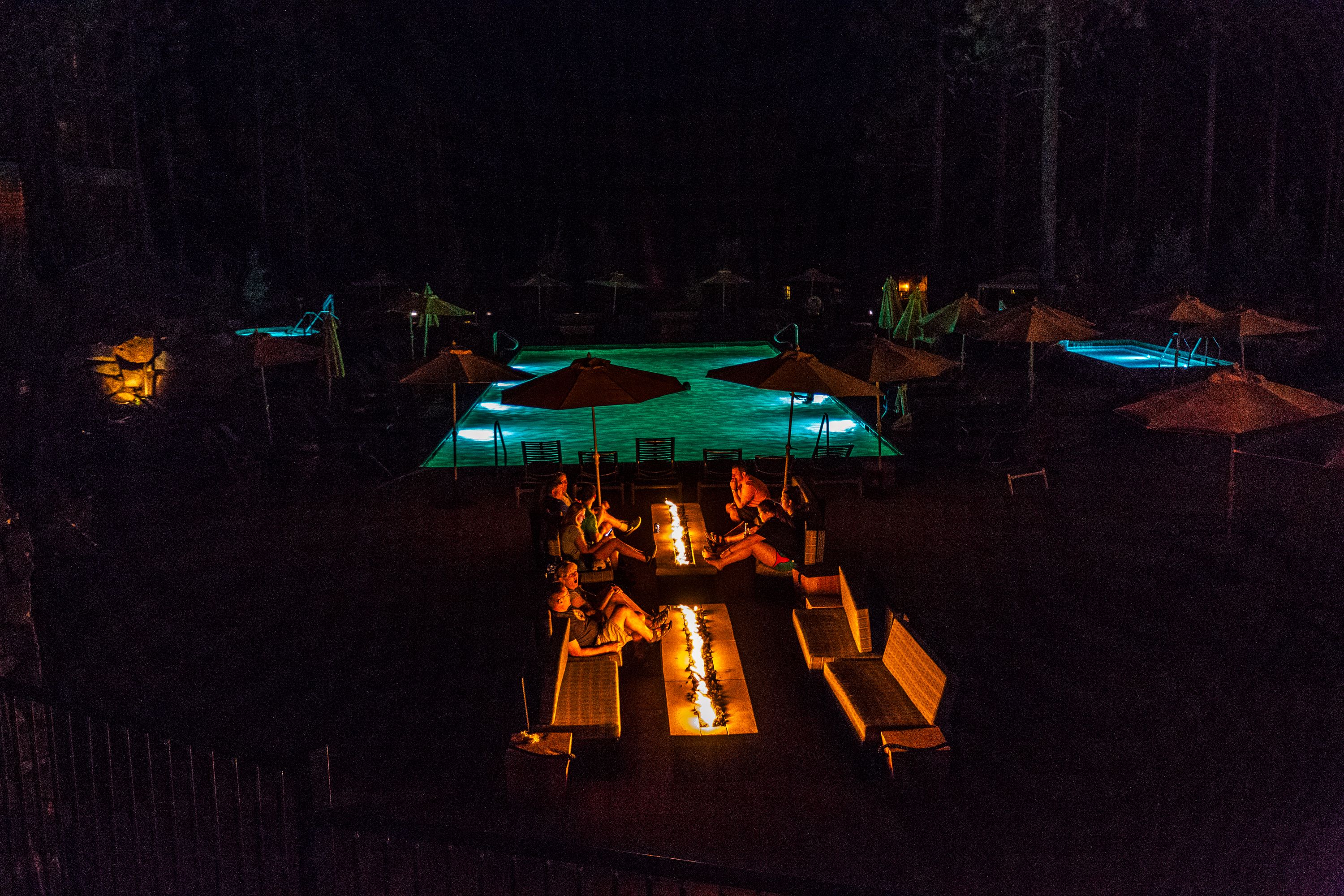 A nighttime outdoor pool area with lounge chairs and umbrellas.