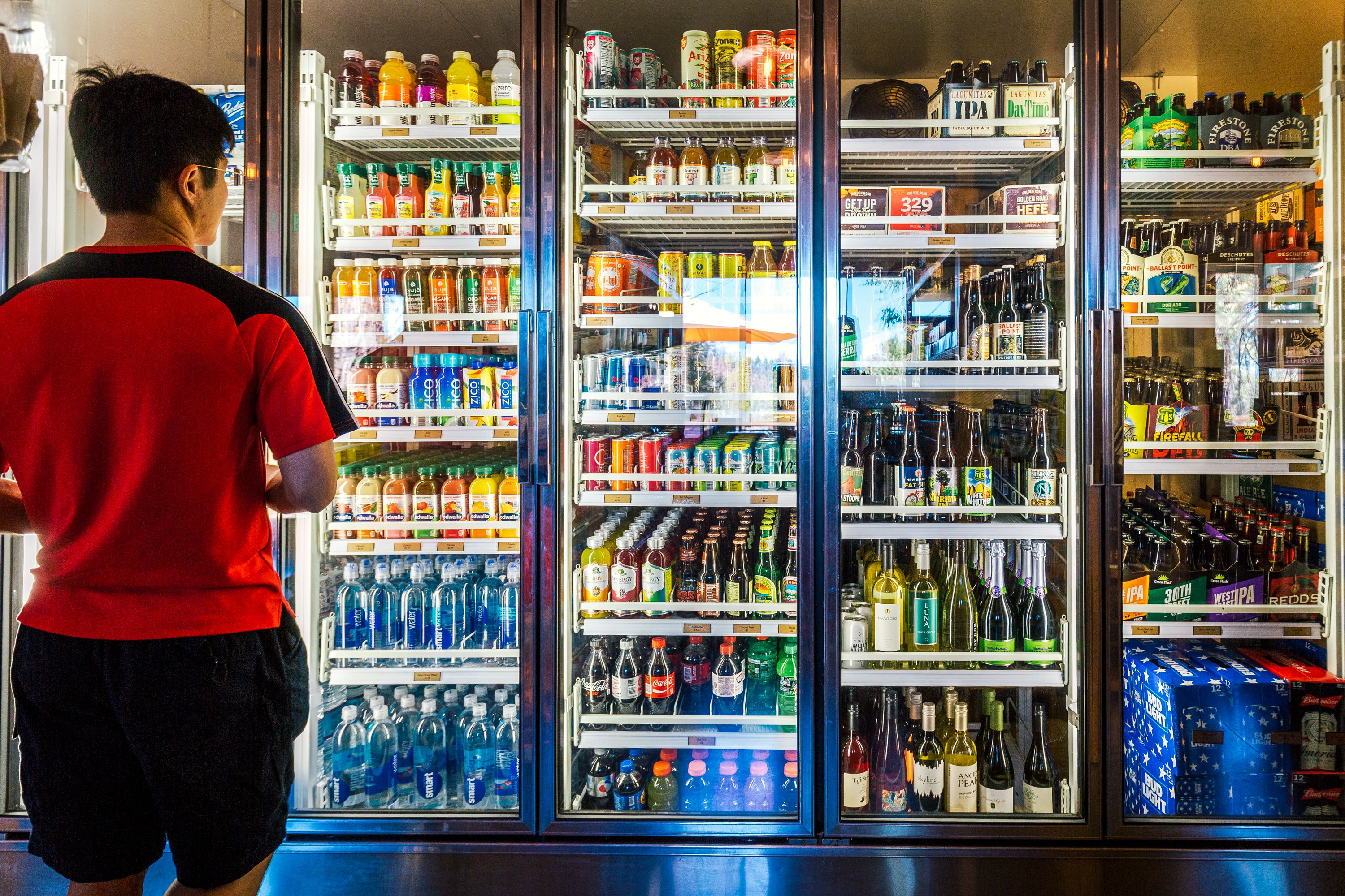 A beverage vending machine stocked with various drinks including sodas, juices, and alcoholic beverages.