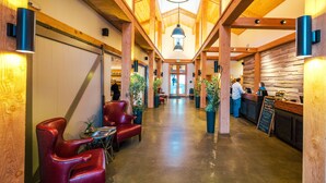 A spacious lobby with wooden beams, leather chairs, and a reception desk.