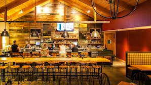A bar with wooden ceiling and walls, bar stools, and a counter with a bartender.