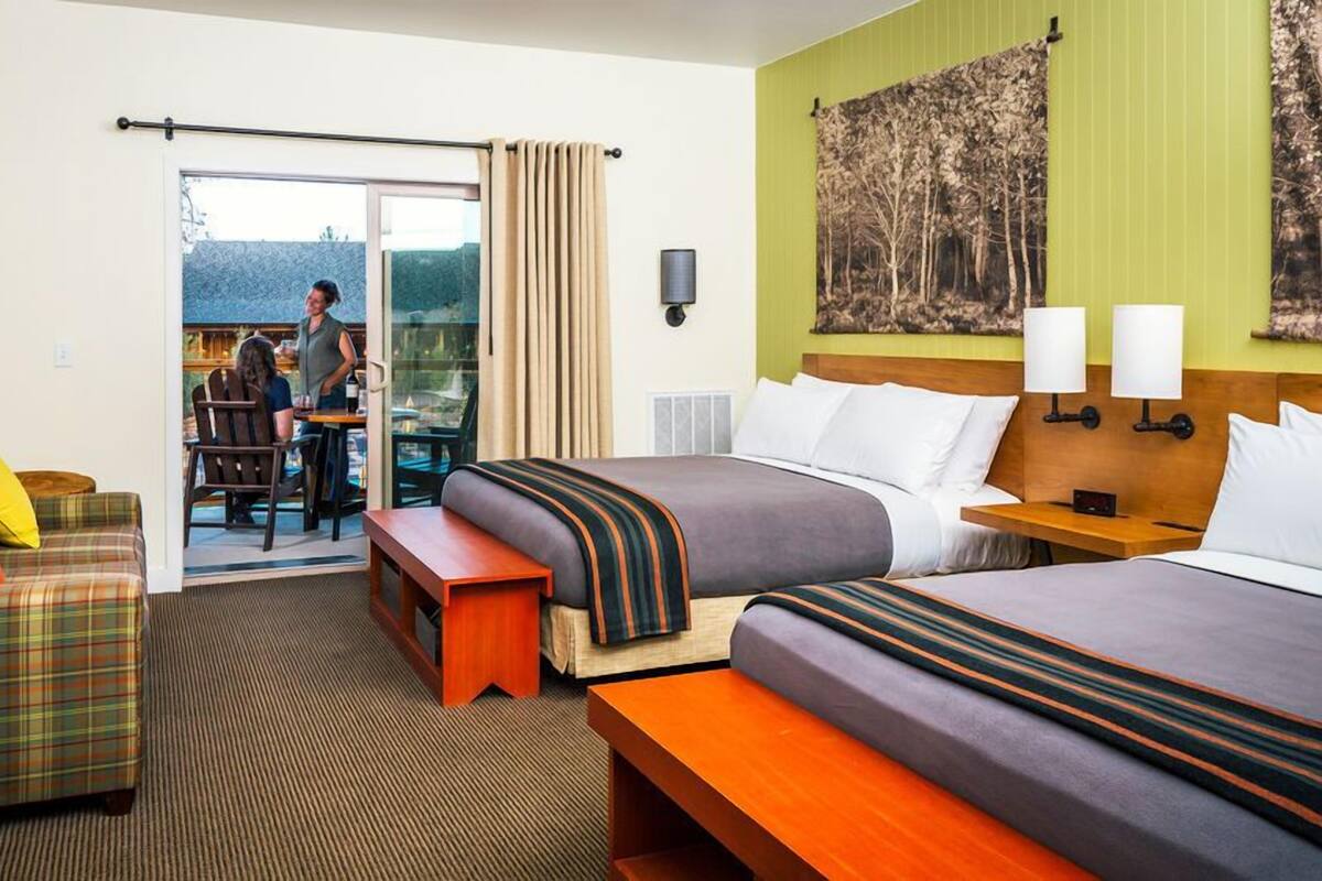 Hotelkamer met een bed, een slaapbank, een klein tafeltje, een bankje, een bureau en uitzicht op het omliggende landschap.
