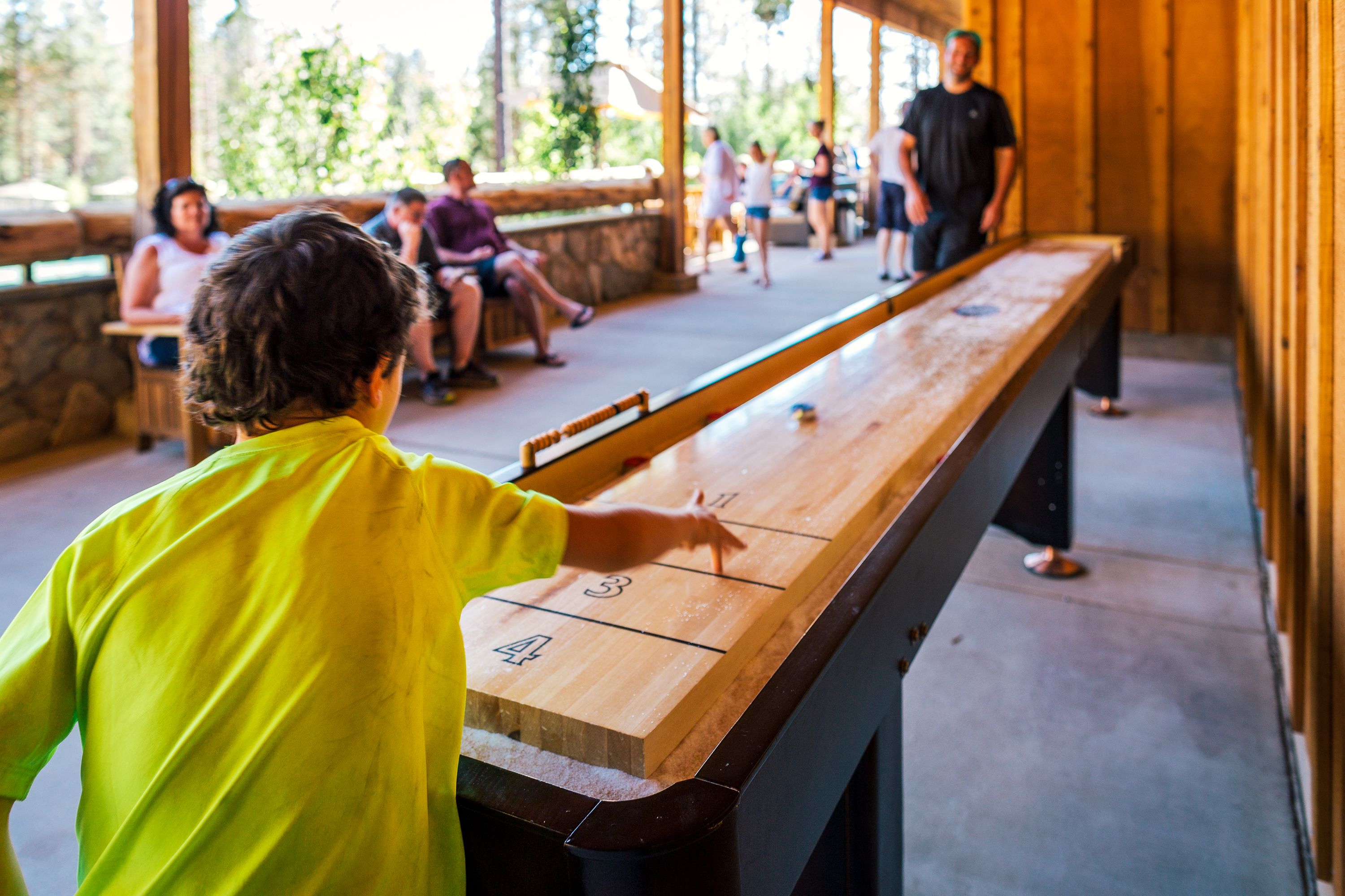Una mesa de shuffleboard con jugadores en un espacio cubierto.