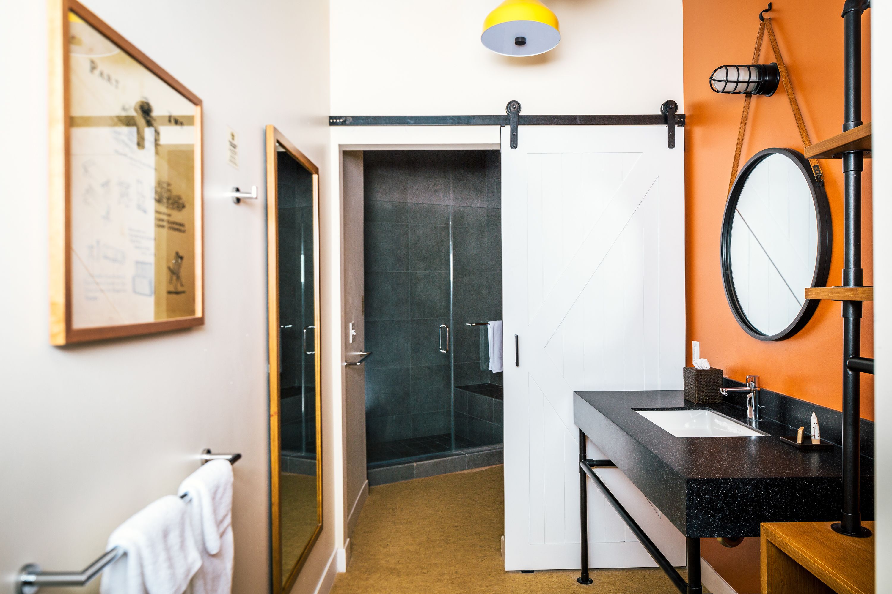 A modern bathroom with a black countertop sink, a mirror, and a shower area.