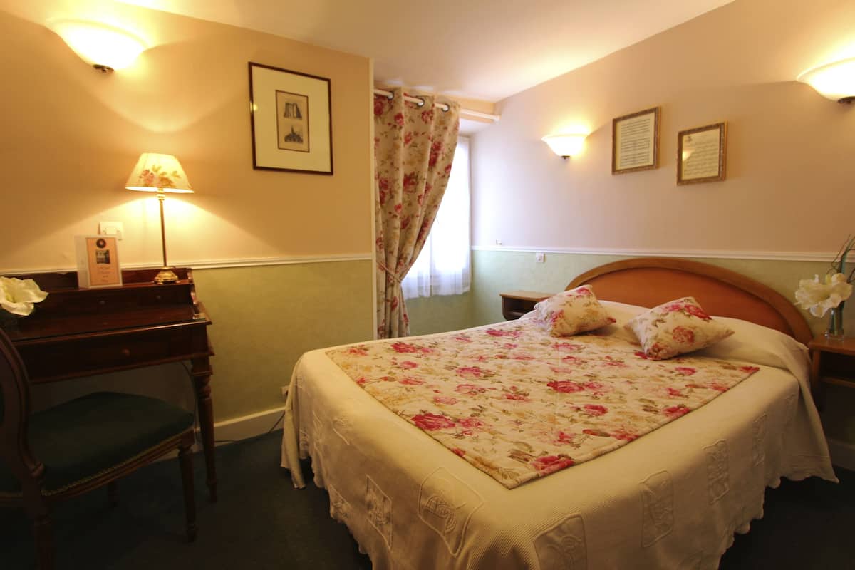 A neatly arranged hotel room with a bed, a desk, and a chair.