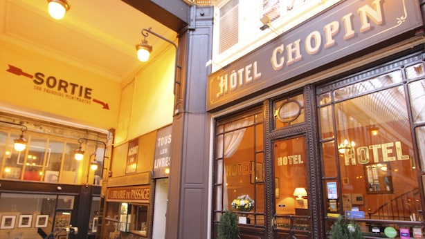 Entrada de um hotel com uma placa indicando "HOTEL CHOPIN" e outra placa com a palavra "SORTIE" acima.