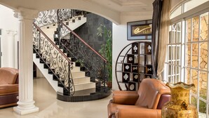 Un interior lujoso con una escalera curva, asientos de cuero y un jarrón decorativo.