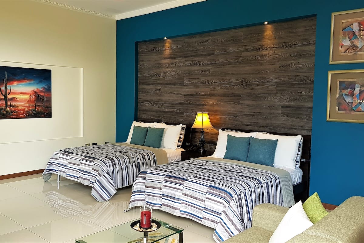 Ein Hotelzimmer mit zwei Betten, einem hölzernen Kopfteil, einem Bild an der Wand und einer Lampe auf dem Nachttisch.