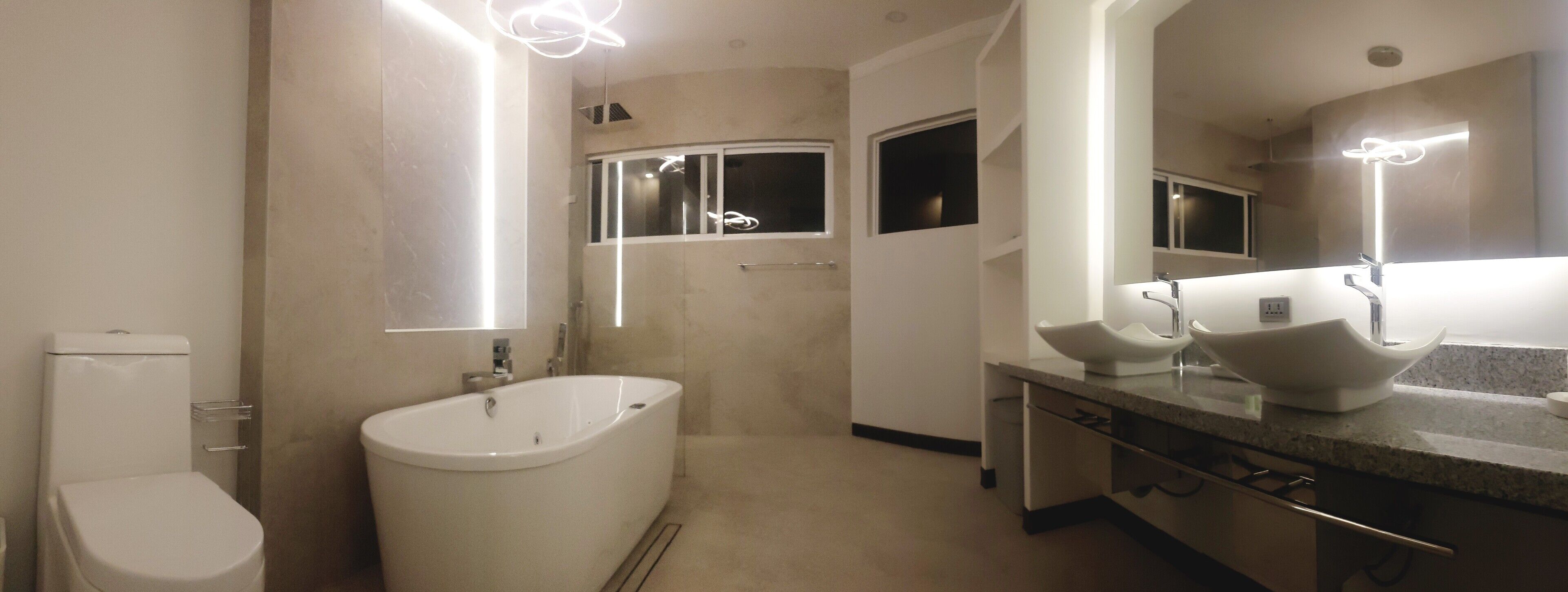 Un baño moderno con una bañera independiente, un lavamanos doble y un espejo grande.