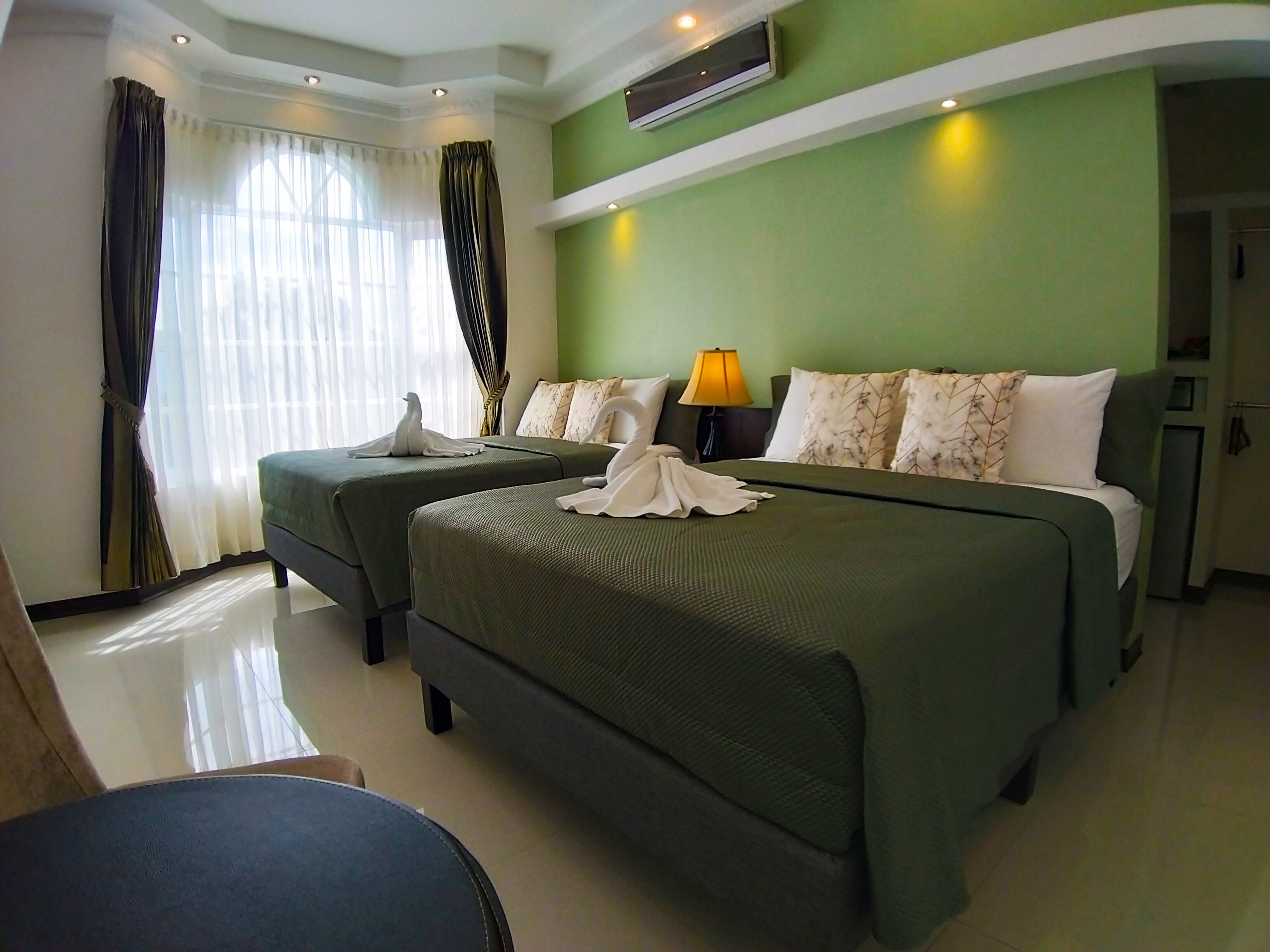 Habitación de hotel con dos camas, un sofá, una lámpara y aire acondicionado central.