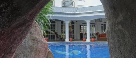 A pool area with a view of a building through an archway.