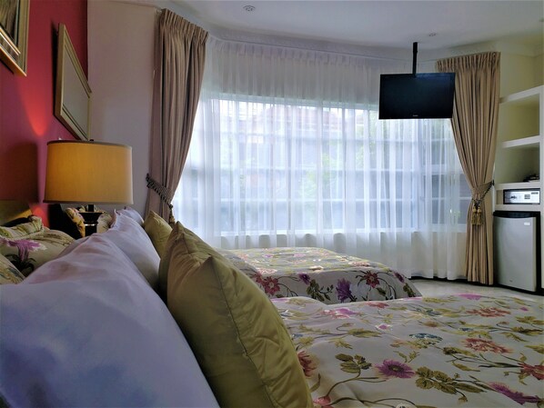 A hotel room with a bed, a TV, a lamp, and a refrigerator.