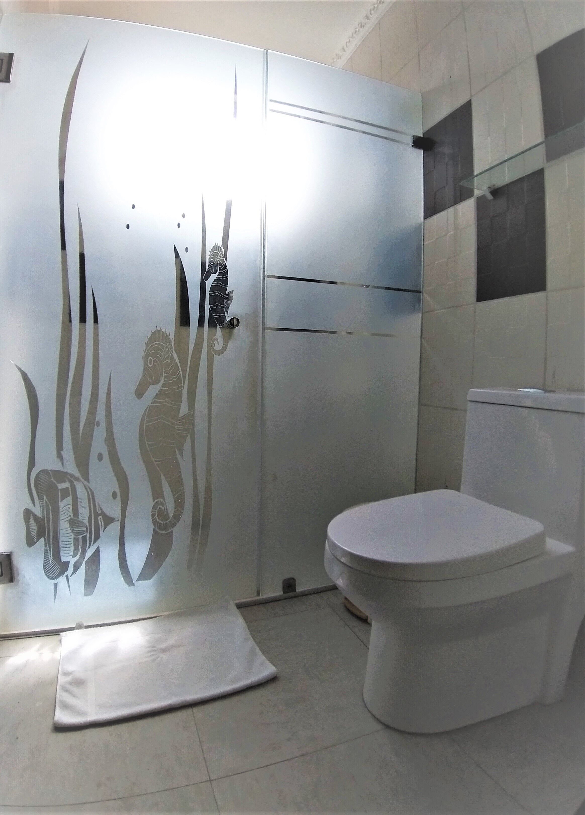 A bathroom with a white toilet, a white sink, and a shower area with a glass door.