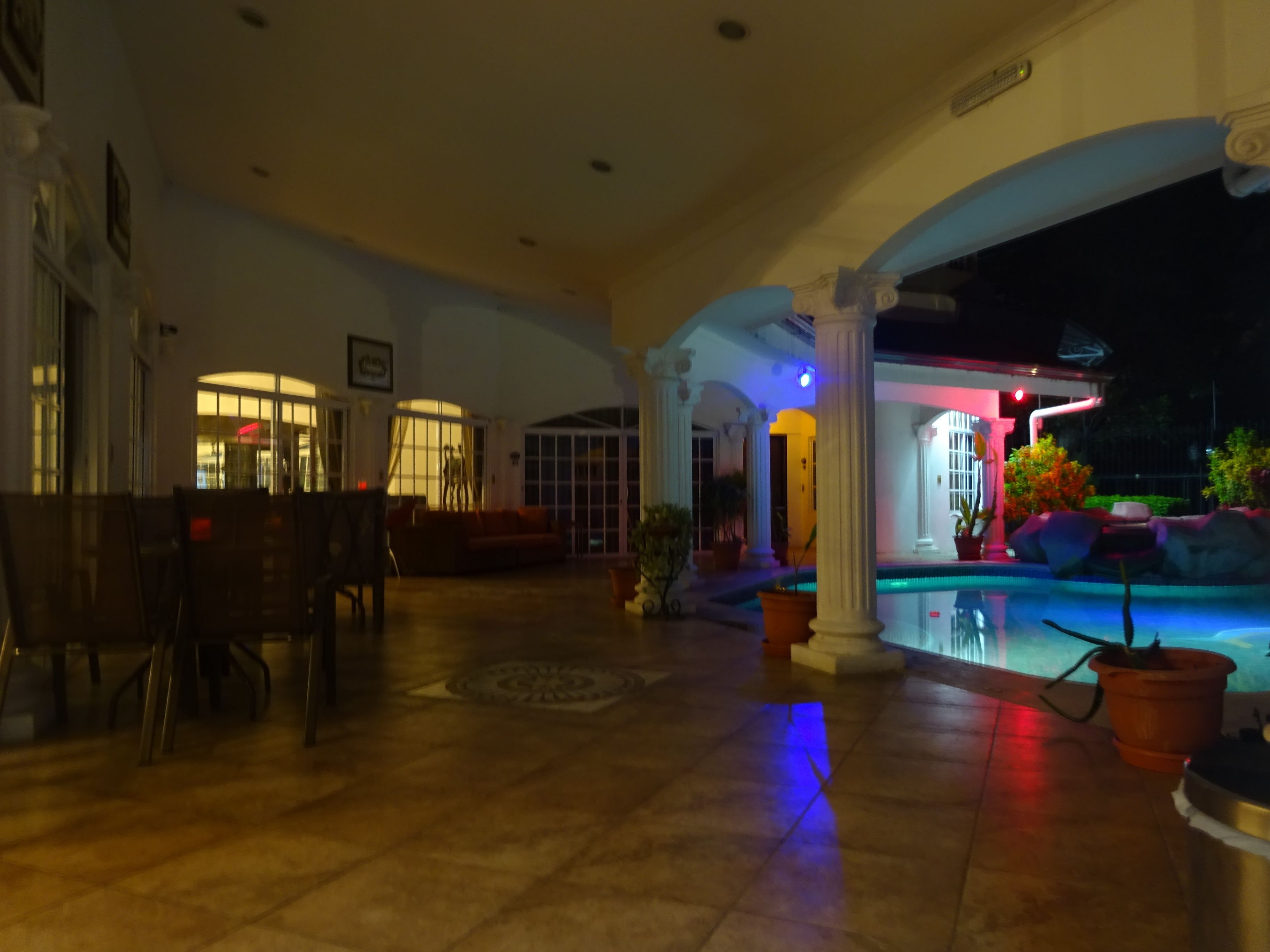 A spacious indoor area with a pool, featuring a seating area with a sofa and chairs, and a tiled floor.