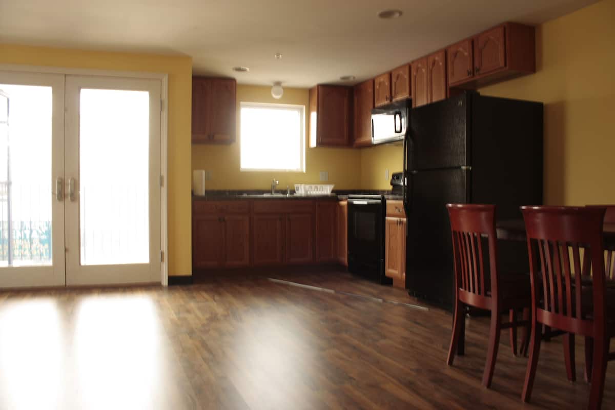 A kitchen with wooden cabinets, a black refrigerator, and a window providing natural light.
