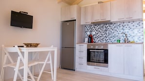 Uma cozinha moderna com armários de madeira clara, uma geladeira de aço inoxidável, forno embutido e painel de azulejos.