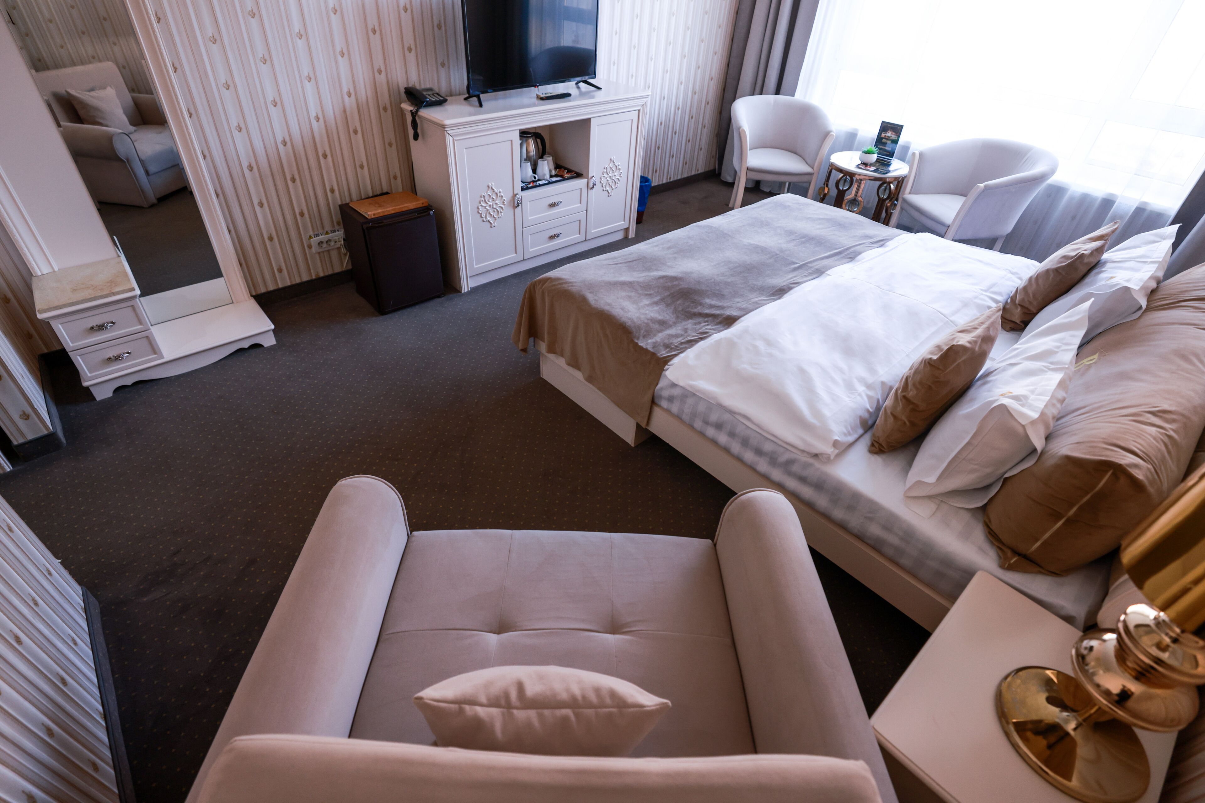 Une chambre d’hôtel avec un lit, un canapé, une télévision, un bureau et une chaise.