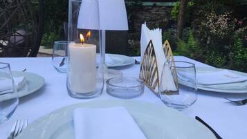 A table set for a meal outdoors with a candle, a lamp, and a napkin with "CARPATTA" written on it.