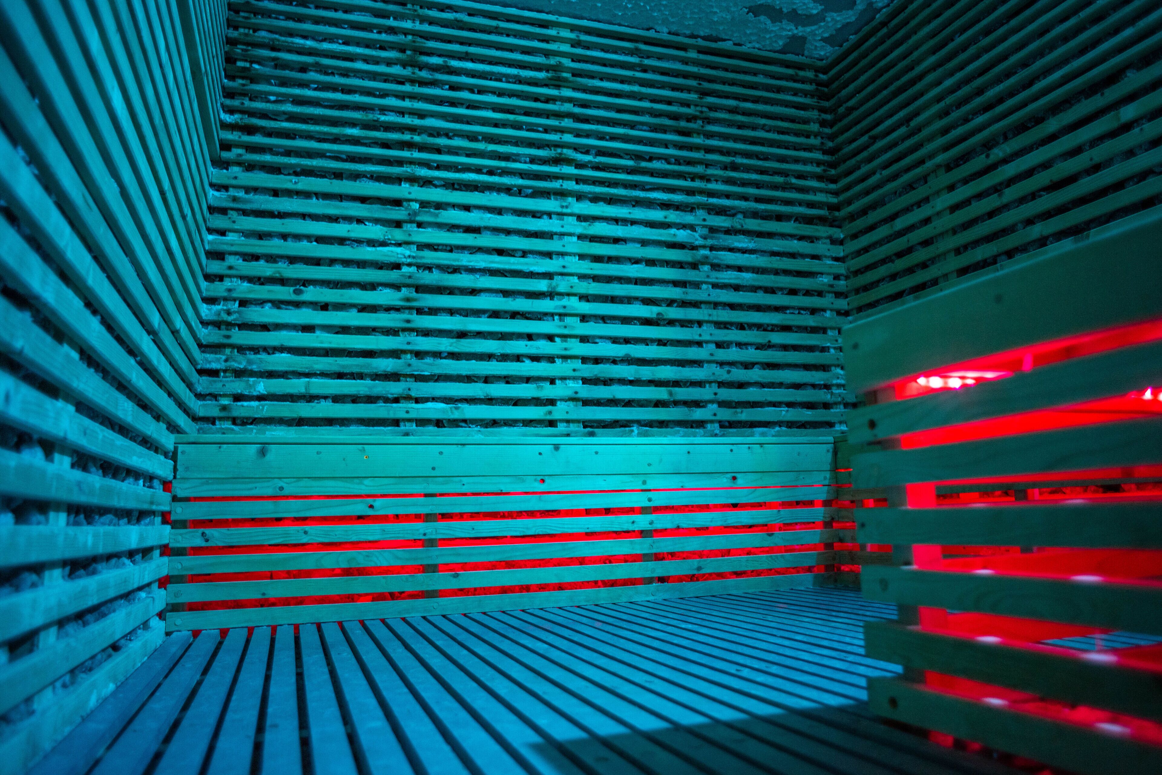 Une pièce aux murs recouverts de lambris en bois et dont le sol est illuminé d’une lumière rouge.